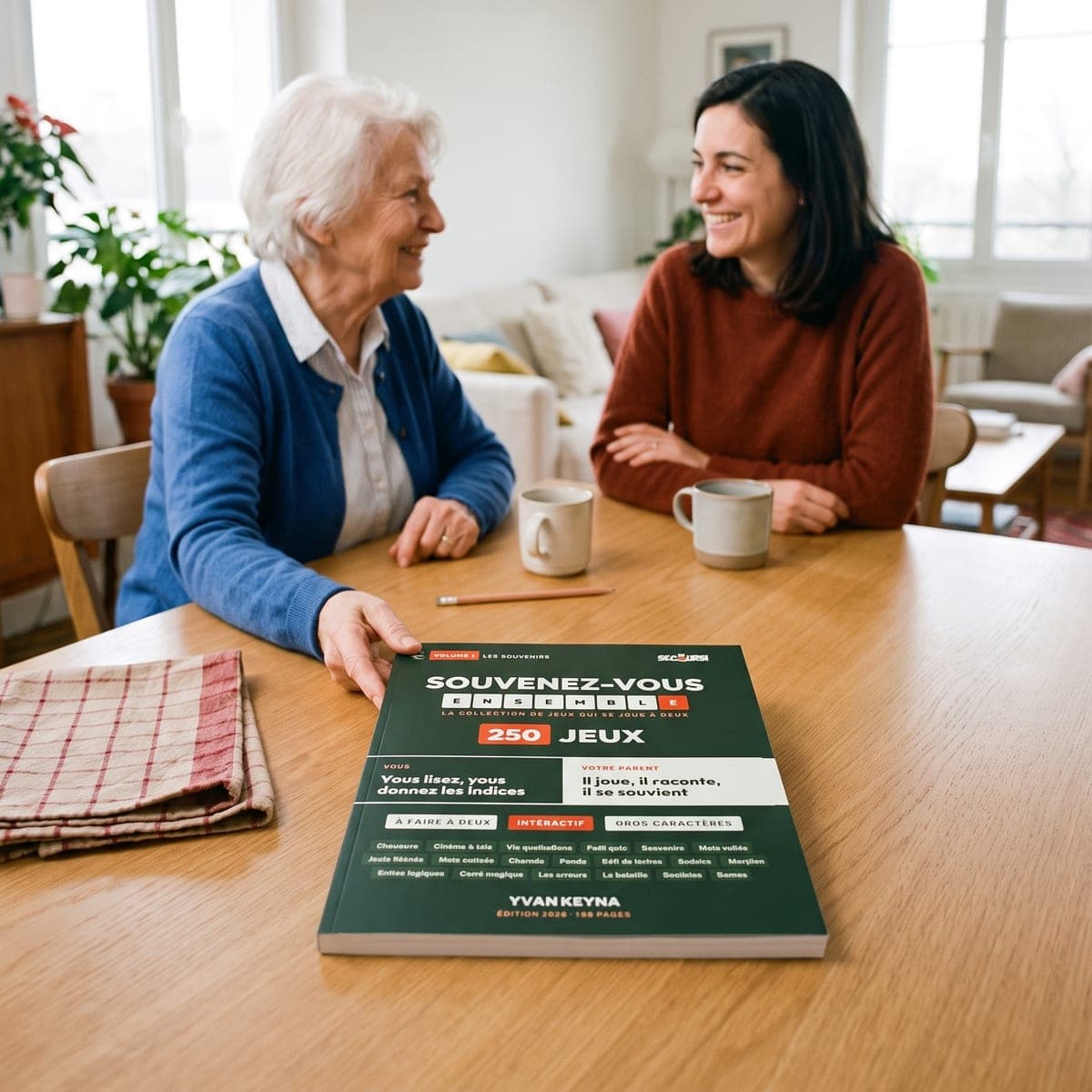 Une mère âgée et sa fille rient ensemble à table, le livre « Souvenez-vous ensemble » posé devant elles
